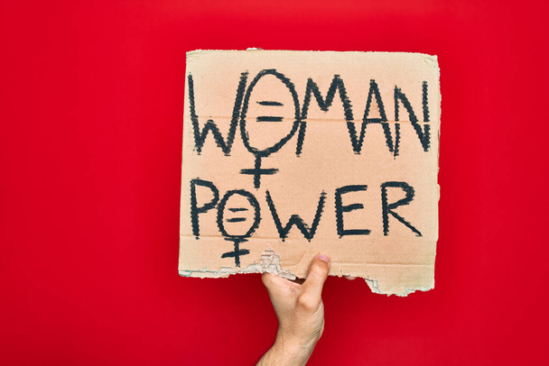 Hermosa mano de hombre sosteniendo pancarta de protesta con mensaje de poder femenino sobre fondo rojo aislado
 - Foto, Imagen