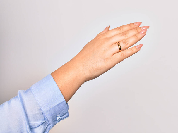 Рука кавказької молодої жінки, що тримає золотий шлюбний перстень над ізольованим білим тлом
 - Фото, зображення