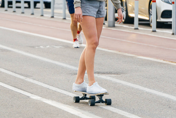 Young girl in shorts on a skateboard in the city. Rest and relaxation in the city in the summer. Lifestyle concept - Fotó, kép