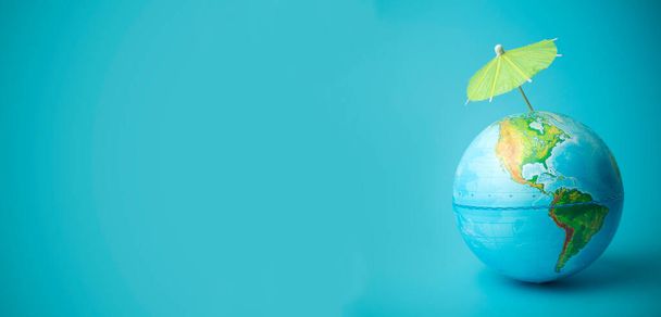 Global warming and climate change on earth concept. Earth globe on a blue background with an umbrella. Protecting the atmosphere from ultraviolet radiation and ozone holes - Photo, Image