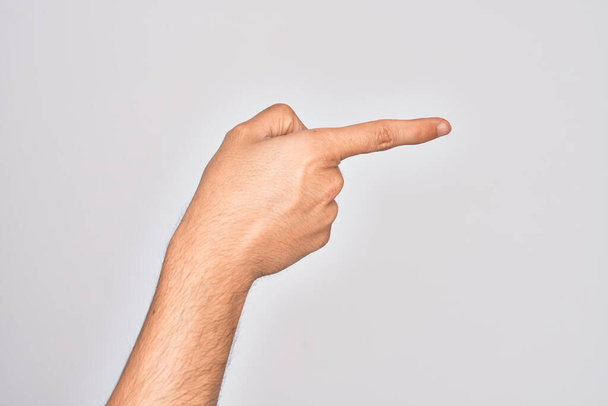 Main de jeune homme caucasien montrant les doigts sur fond blanc isolé pointant avec l'index sur le côté, suggérant et sélectionnant un choix - Photo, image