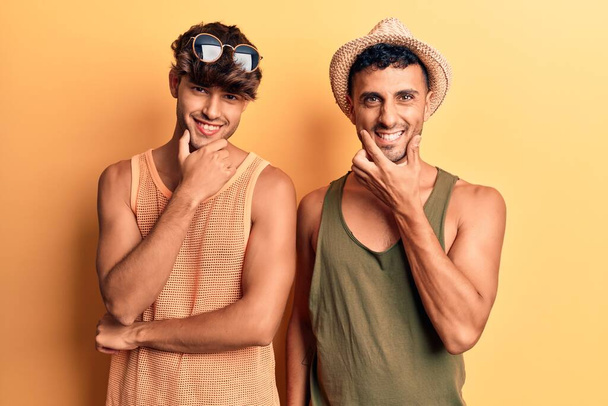 Mladý gay pár v letních šatech, sebevědomě se usmívající do kamery se zkříženýma rukama a rukou zvednutou na bradě. pozitivní myšlení.  - Fotografie, Obrázek