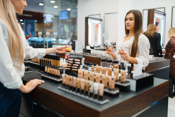 Cosmetician at the counter and woman in cosmetics store. Luxury beauty shop salon, female customer and beautician in fashion market - Zdjęcie, obraz