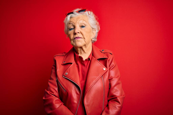 Senior beautiful grey-haired woman wearing casual red jacket and sunglasses Relaxed with serious expression on face. Simple and natural looking at the camera. - Fotografie, Obrázek