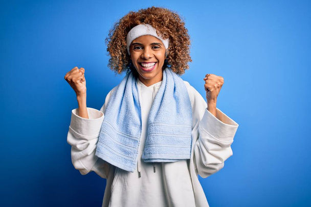 スポーツウェアとタオルを身に着けてスポーツを行う若いアフリカ系アメリカ人のスポーツ女性は驚きと腕を上げて開いて目で成功のために驚いています。勝者のコンセプト. - 写真・画像