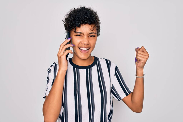Young beautiful african american afro woman having conversation talking on the smartphone screaming proud and celebrating victory and success very excited, cheering emotion - Foto, afbeelding