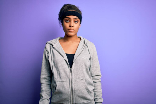 Young african american sportswoman doing sport wearing sportswear over purple background Relaxed with serious expression on face. Simple and natural looking at the camera. - Fotografie, Obrázek