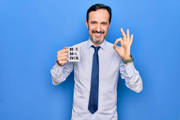 Середньовіччя елегантний бізнесмен п'є чашку кави з кращим татом коли-небудь повідомлення роблячи знак з пальцями, посміхаючись дружній жест відмінний символ
 - Фото, зображення