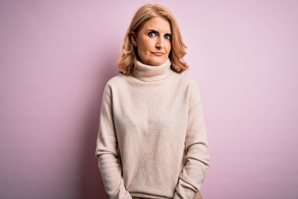Middle age beautiful blonde woman wearing casual turtleneck sweater over pink background skeptic and nervous, frowning upset because of problem. Negative person. - Photo, Image