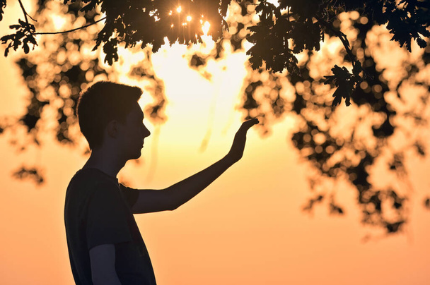 Closeup portrait young man praying hands up against sunset - Photo, Image