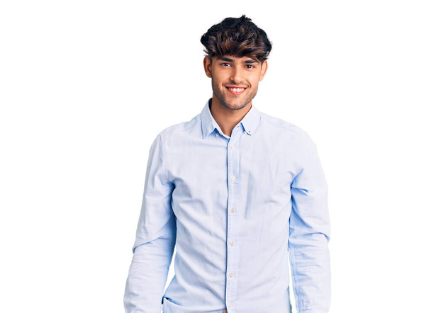Jonge Spaanse man draagt casual shirt met een vrolijke en coole glimlach op zijn gezicht. gelukkig persoon.  - Foto, afbeelding