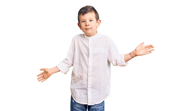 Χαριτωμένο ξανθό παιδί φορώντας κομψό πουκάμισο ανίδεοι και σύγχυση έκφραση με τα χέρια και τα χέρια ψηλά. έννοια της αμφιβολίας.  - Φωτογραφία, εικόνα
