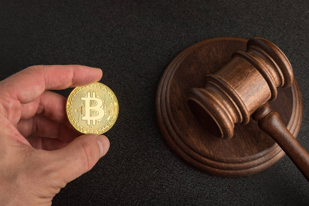 Law or auction gavel and bitcoins in hand. Dispute resolution on bitcoin frauds. Cryptocurrency legislation - Photo, Image