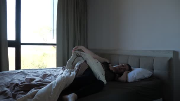 young woman in pajama awakes in bed and walks to window - Кадри, відео