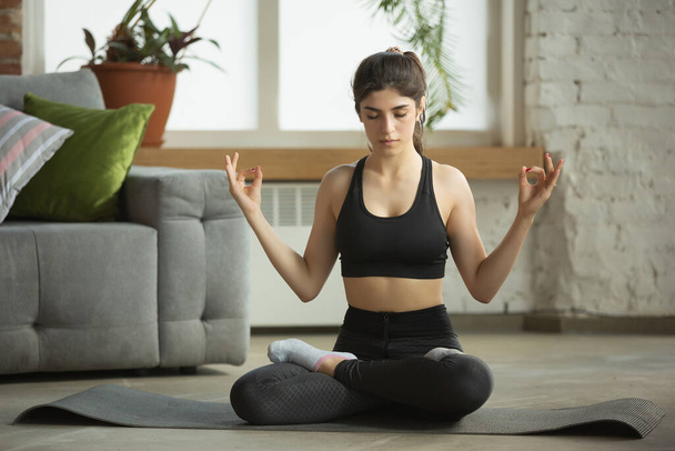 Sportieve jonge moslim vrouw die online yoga lessen neemt en thuis oefent - Foto, afbeelding