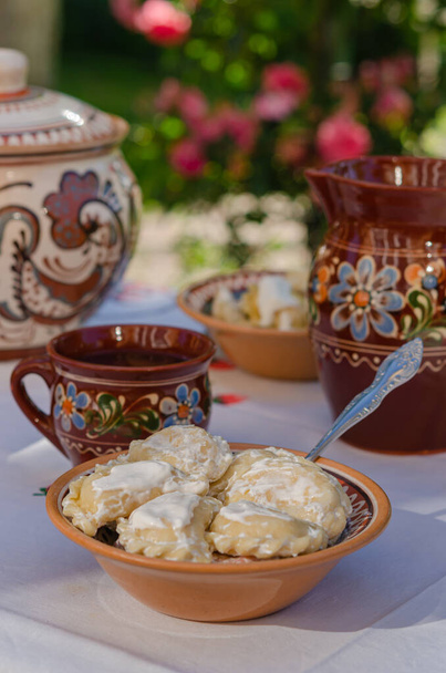 Domácí pierogi v jílu etnických ukrajinských jídel na stole v letní zahradě. Národní kuchyně, životní styl - Fotografie, Obrázek