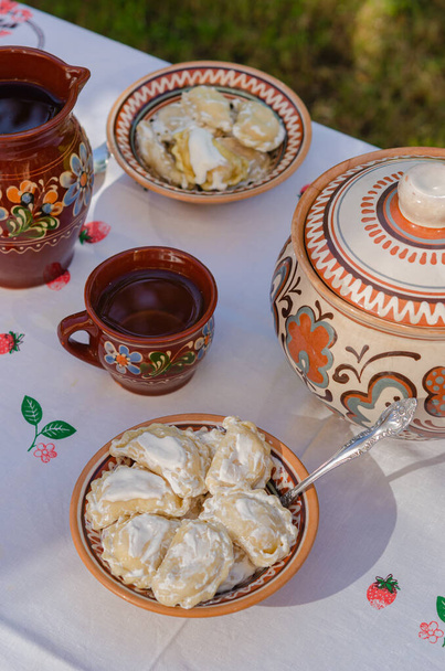 Pierogi fatti in casa in argilla piatti etnici ucraini su un tavolo nel giardino estivo. Cucina nazionale, stile di vita - Foto, immagini