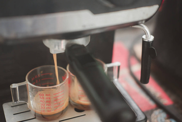 Dubbele espresso wordt gemaakt van een commerciële machine in een lokale coffeeshop. Selectieve focus - Foto, afbeelding