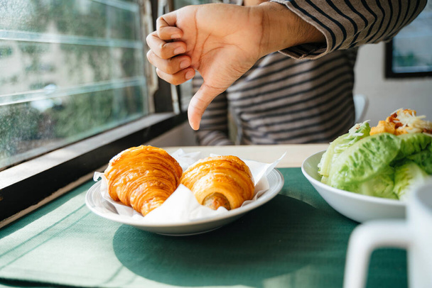 Imagem cortada da mão de um homem, ele dá um polegar croissant para baixo porque seu sabor é realmente ruim
. - Foto, Imagem