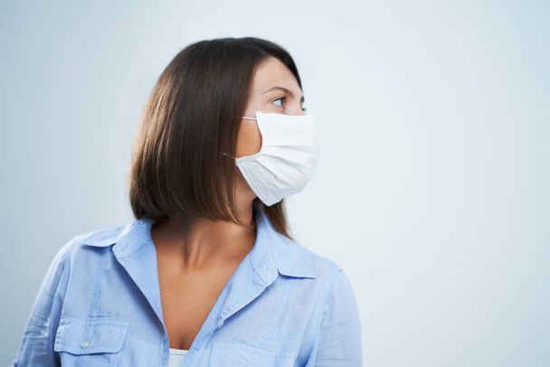 Aantrekkelijke vrouw dragen beschermende masker geïsoleerd over witte achtergrond - Foto, afbeelding