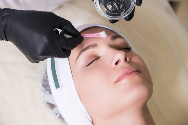 Cosmetoloog arts toe te passen alkalisch wassen peeling op client gezicht in haar kabinet in kliniek - Foto, afbeelding