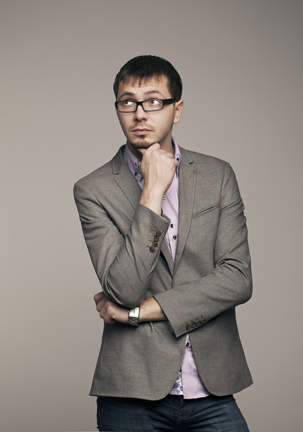 Young man thinking. Studio photo on gray background. - Foto, Imagen