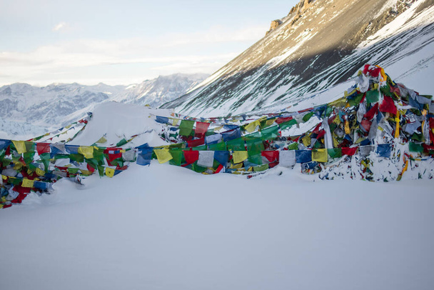 Flagi modlitewne na szczycie Thorung La Pass pokryte silnym śniegiem, tor Annapurna, Nepal - Zdjęcie, obraz