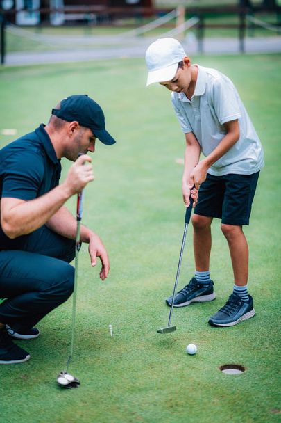 Навчання гольфу. Хлопчик практикує введення з інструктором
 - Фото, зображення
