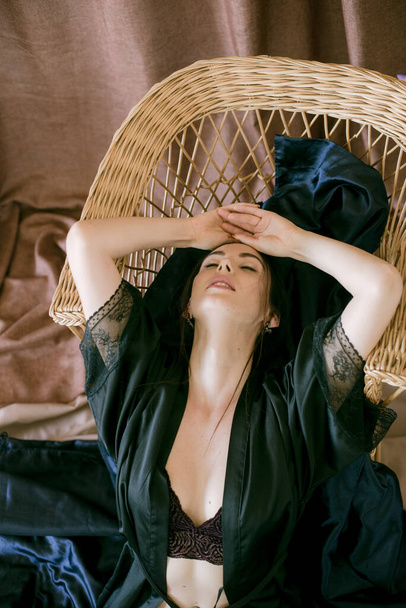 Young attractive girl with dark hair in a black silk robe in a boudoir setting. Beauty and Fashion - Foto, Imagen