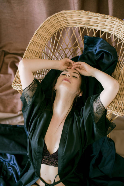 Young attractive girl with dark hair in a black silk robe in a boudoir setting. Beauty and Fashion - Фото, зображення