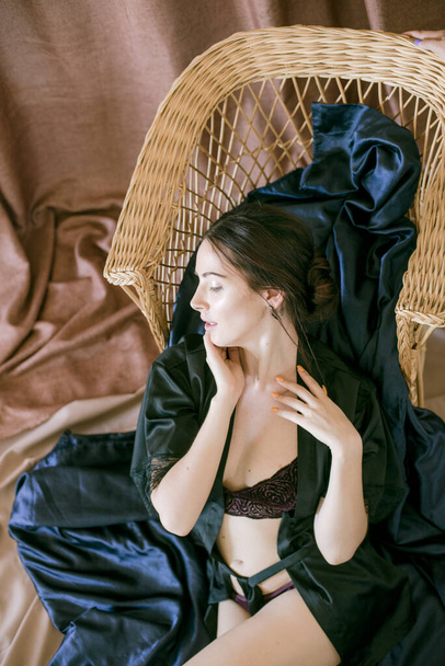 Young attractive girl with dark hair in a black silk robe in a boudoir setting. Beauty and Fashion - Fotografie, Obrázek