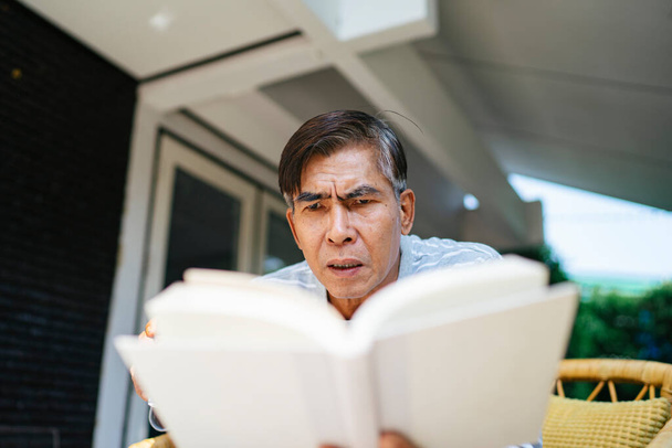 灰色の髪の老人は本を読んでプロットについて失敗します. - 写真・画像