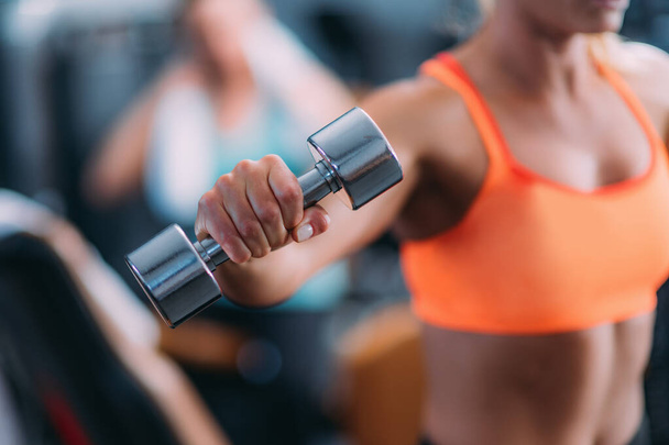 Attrayant jeune femme faisant de l'exercice avec des poids dans la salle de gym moderne - Photo, image