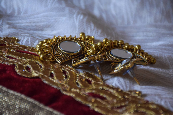 Фотографія чудових індійських ювелірних виробів з золотого дзеркала на білому тлі .традиційні індійські модні ювелірні вироби, зосереджені на об'єкті в Бангалорі, місті Карнатака Індія..  - Фото, зображення