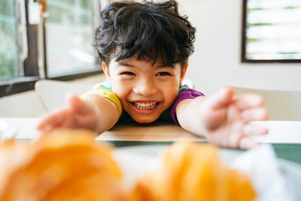 Счастливый маленький мальчик наслаждайтесь завтраком, колбасные круассаны и салат
. - Фото, изображение