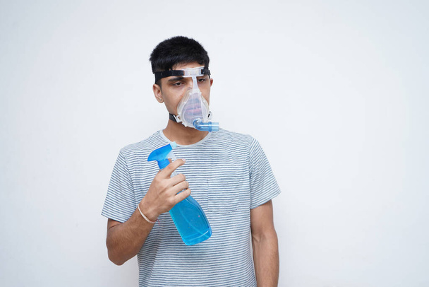 Young Asian teen boy using sanitizer while wearing oxygen mask. - Zdjęcie, obraz