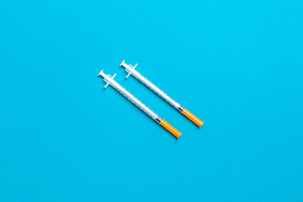 Draufsicht auf zwei Insulinspritzen vor buntem Hintergrund mit Kopierraum. Hohes Maß an Glukose. - Foto, Bild