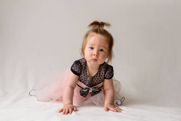 Little girl learns to crawl. The girl is wearing a dress. - Photo, Image