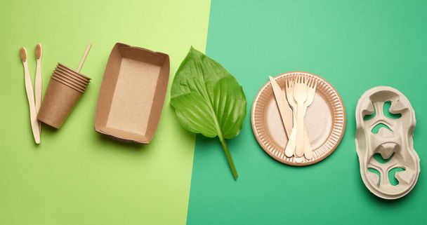 disposable paper utensils from brown craft paper and recycled materials on a green background, plastic rejection concept, zero waste  - Foto, Imagen