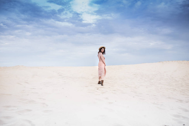  fille dans désert promenade avec cheveux foncés shorts, sable et blu ciel arrière-plan - Photo, image
