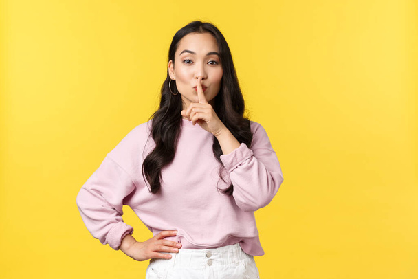People emotions, lifestyle and fashion concept. Stylish attractive asian woman hush, say shhh as asking keep secret or be quiet, press finger to lips shushing, standing yellow background - Fotografie, Obrázek