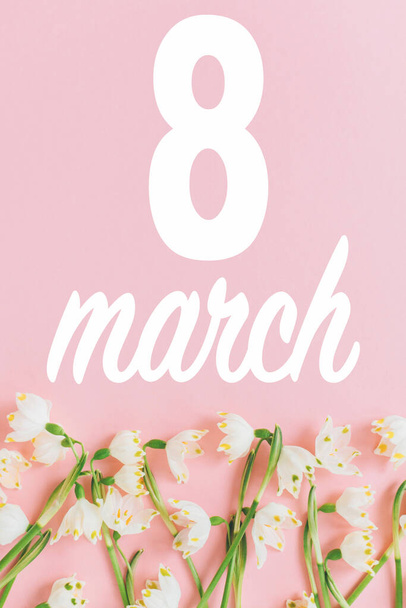 Joyeuse journée des femmes. 8 Mars texte sur les fleurs fraîches du printemps sur fond rose pastel. Modèle de carte de vœux floral élégant. Journée internationale de la femme. - Photo, image