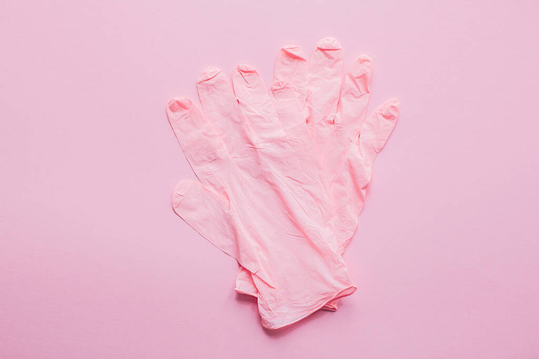 Roze handschoenen op roze achtergrond plat lay. Coronavirus pandemie. Blijf veilig. Preventie van virusepidemie. Veilig winkelen en wandelen buiten in quarantaine. Blijf veilig thuis. - Foto, afbeelding