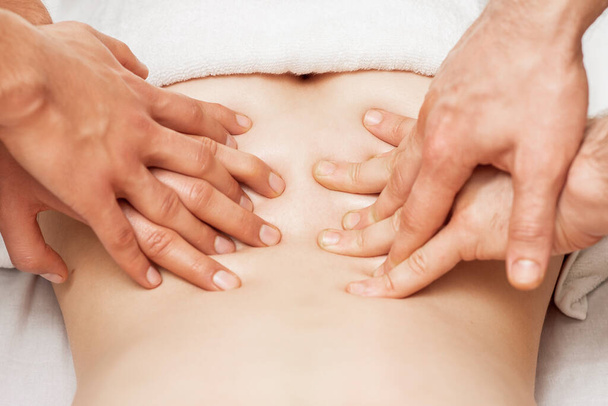 Mujer recibiendo masaje de espalda con cuatro manos de dos terapeutas masculinos de cerca
. - Foto, Imagen