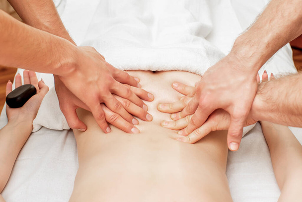 Mulher recebendo massagem nas costas com quatro mãos de dois terapeutas do sexo masculino de perto
. - Foto, Imagem