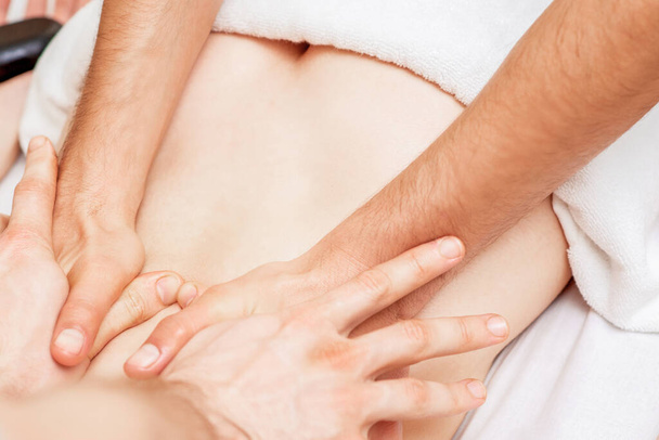 Žena dostává masáž zad se čtyřmi rukama dvou mužských terapeutů zblízka. - Fotografie, Obrázek