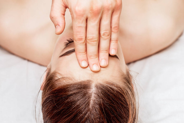 Top view woman receiving forehead massage by fingers of massage therapist. - Φωτογραφία, εικόνα
