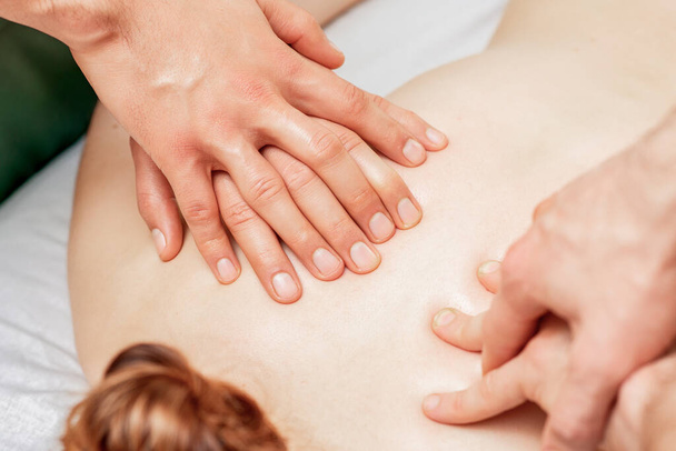 Mulher recebendo massagem nas costas com quatro mãos de dois terapeutas do sexo masculino de perto
. - Foto, Imagem