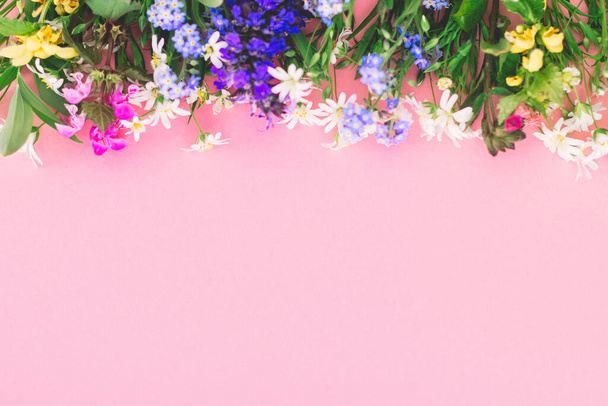 ピンクの紙の背景にカラフルな春の野の花の花のフラットレイアウト、テキストのためのスペース。花のグリーティングカードテンプレート。幸せな母の日の概念。春だ。春の花の国境を開花させる - 写真・画像