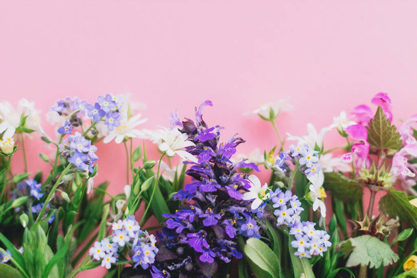 Vadvirágok színes határ rózsaszín papír háttér, lapos feküdt helyet a szövegnek. Virágzó tavaszi virágok, virágüdvözlő kártya sablon. Boldog anyák napi koncepciót. Helló tavasz! - Fotó, kép